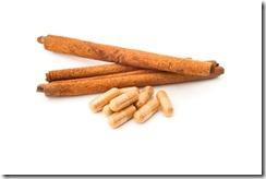 herbal powder in capsule and cinnamon on white background