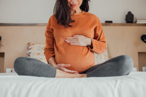 pregnant woman sitting on bed at home