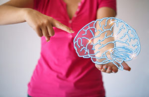 woman ponting to image of brain held in other hand