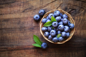 Fresh ripe garden blueberries in a small bowl on dark rustic wooden table
