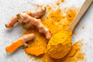 Fresh root and turmeric powder on a surface, overview 