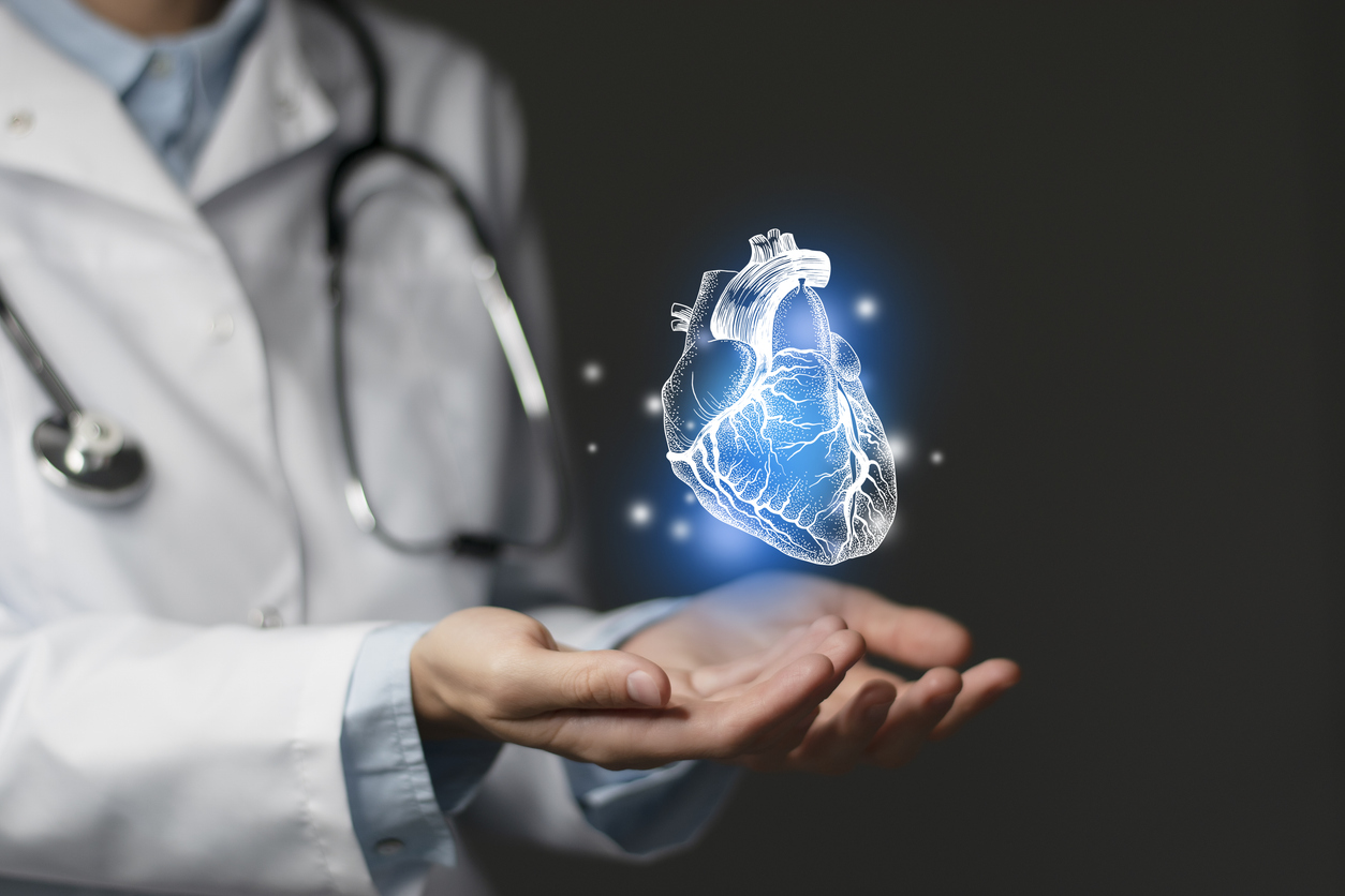 Heart issues medical concept. Photo of female doctor with hands holding an image of a heart - dark background